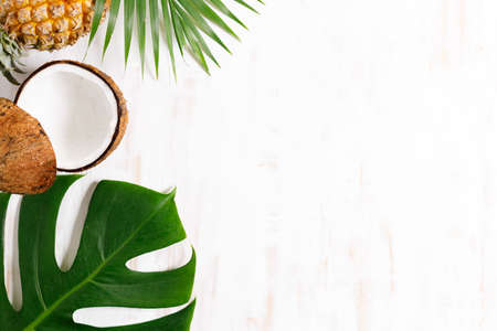 Tropical leaves monstera with fruits on a wooden table background. Top view. Minimal summer...