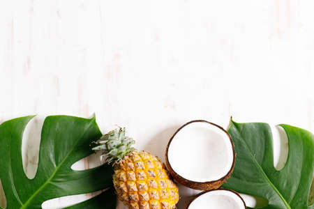 Tropical leaves monstera with fruits on a wooden table background. Top view. Minimal summer background.の写真素材