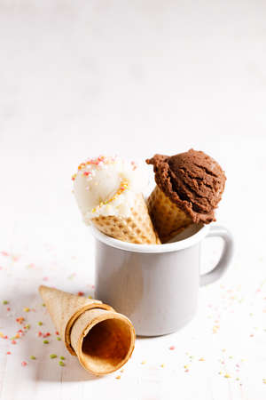Waffle ice cream cones on with ice cream on white wooden background. Sweet and summer concept.