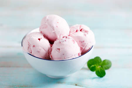 Ice cream scoops in white bowl on wooden table background, closeupの写真素材