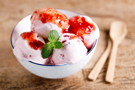 Ice cream scoops in white bowl on wooden table background, closeupの写真素材