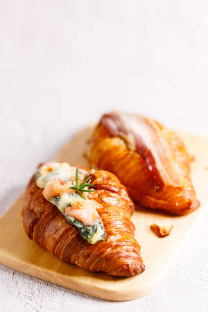 Fresh baked croissants with spinach, salmon and bacon on white concrete background. Breakfast with croissants.の写真素材