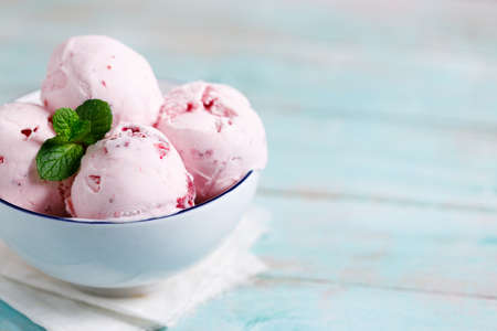 Ice cream scoops in white bowl on wooden table background, closeupの写真素材