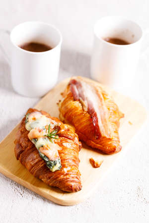Fresh baked croissants with spinach, salmon and bacon on white concrete background. Breakfast with croissants.の写真素材