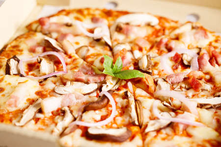 Fresh Italian pizza with mushrooms and bacon in a box, closeup.の写真素材
