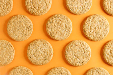 Oatmeal cookie on orange color background. Healthy round cookies. Top view.の写真素材