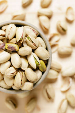 pistachio nuts in ceramic bowl on wooden table background.の写真素材