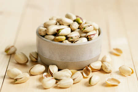 pistachio nuts in ceramic bowl on wooden table background.の写真素材