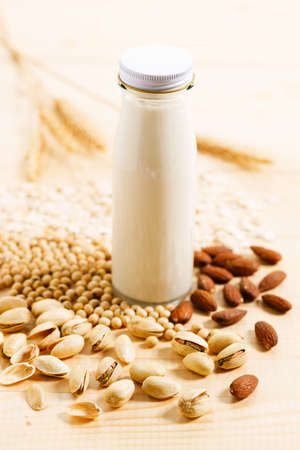 substitute milk in glass bottle on wooden table.Various vegan plant based milk and ingredients, top view.の写真素材