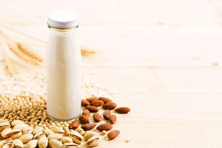 substitute milk in glass bottle on wooden table.Various vegan plant based milk and ingredients, top view.の写真素材