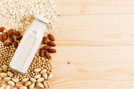 substitute milk in glass bottle on wooden table.Various vegan plant based milk and ingredients, top view.の写真素材