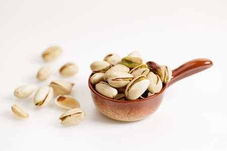 pistachio nuts in ceramic bowl on white background.の写真素材