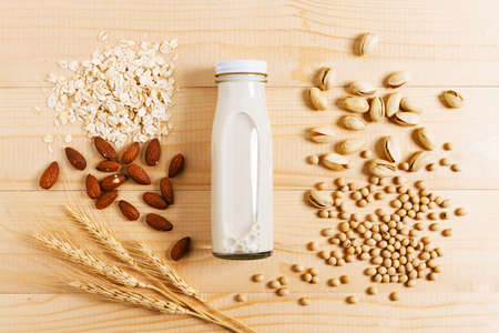 substitute milk in glass bottle on wooden table.Various vegan plant based milk and ingredients, top view.の写真素材