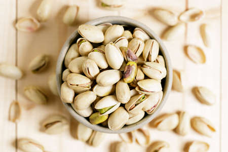 pistachio nuts in ceramic bowl on wooden table background.の写真素材