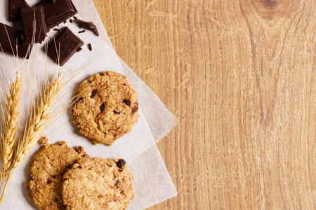 chocolate cookies with chocolate pieces on wooden table, close upの写真素材