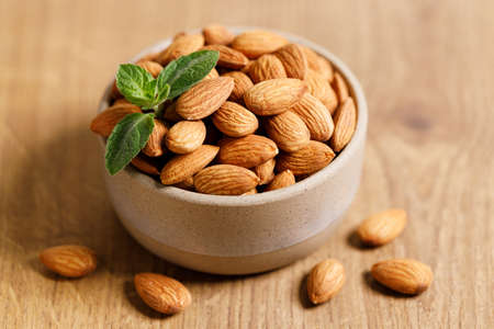 Almonds  in ceramic bowl on wooden table, closeupの写真素材