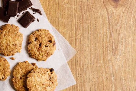 chocolate cookies with chocolate pieces on wooden table, close upの写真素材