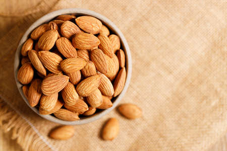Almonds  in ceramic bowl on wooden table, closeupの写真素材
