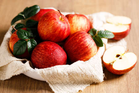 red ripe apples with leaves in white plate with napkin, closeup.の写真素材