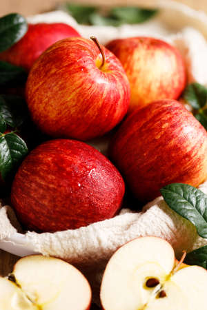 red ripe apples with leaves in white plate with napkin, closeup.の写真素材