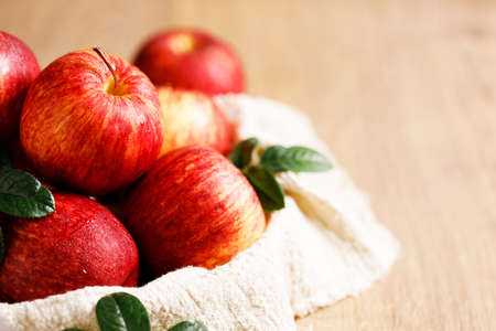 red ripe apples with leaves in white plate with napkin, closeup.の写真素材
