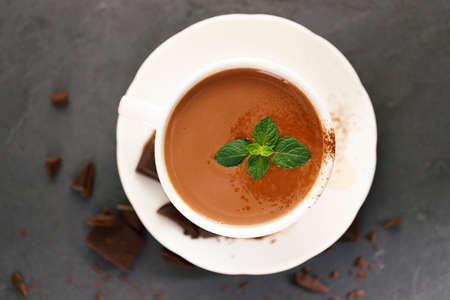 Hot chocolate in white cup with chocolate pieces and mint leaves on dark background.の写真素材