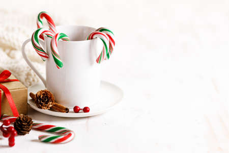candy canes with red, green and white color in a white cup on white wooden background.の写真素材