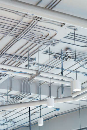 Pipes and conduits in a white rustic ceiling background. Look up view. construction background concept.の写真素材