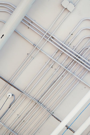Pipes and conduits in a white rustic ceiling background. Look up view. construction background concept.の写真素材
