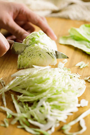 Closeup of women hand chopping fresh vegetable on cutting board. preparing a healthy meal concept.の写真素材