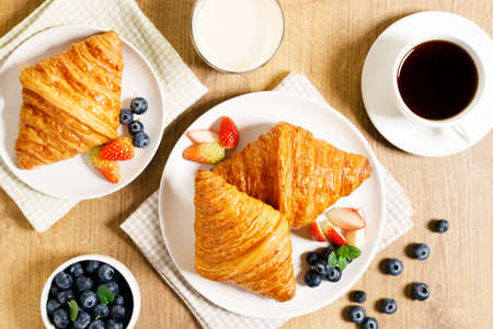 Croissants and fresh berries with coffee for healthy breakfast. On wooden table background.
Top view.の写真素材