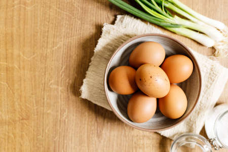 top view of raw eggs on kitchen wooden table with fresh green spring onion.
fresh and nutritious brown eggs. concept for egg and easy healthy breakfast.の写真素材
