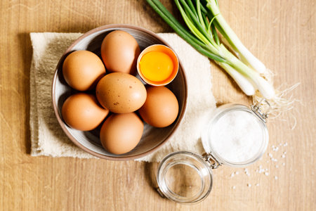 top view of raw eggs on kitchen wooden table with fresh green spring onion.
fresh and nutritious brown eggs. concept for egg and easy healthy breakfast.の写真素材