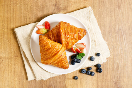 Croissants and fresh berries with coffee for healthy breakfast. On wooden table background.
Top view.の写真素材