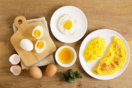 Cooking eggs in deferent way like boiled egg, fried egg and scrambled egg on wooden table. Top view.の写真素材