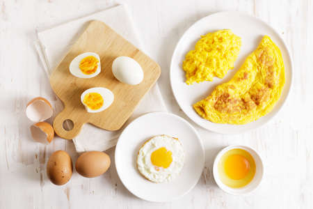 Cooking eggs in deferent way like boiled egg, fried egg and scrambled egg on wooden table. Top view.の写真素材