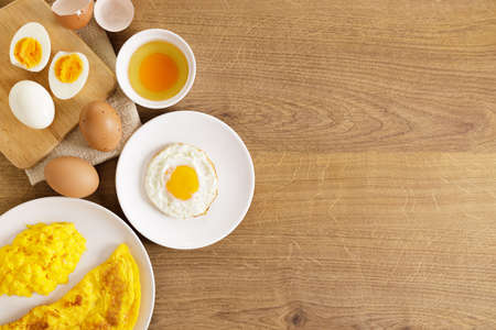 Cooking eggs in deferent way like boiled egg, fried egg and scrambled egg on wooden table. Top view.の写真素材