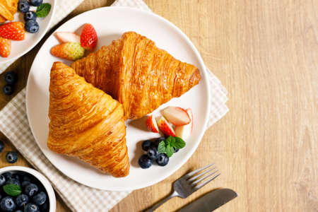 Croissants and fresh berries with coffee for healthy breakfast. On wooden table background.
Top view with copy space.の写真素材