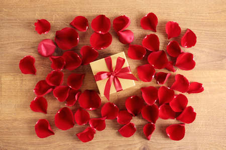 red rose flowers and gift box on wooden background. valentineâs day and love concept. top view.の写真素材