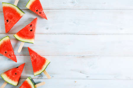 watermelon slice popsicles on light blue wooden background. top view.の写真素材