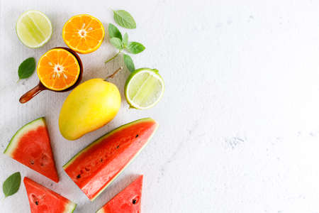 variety of summer fruits, watermelon mango lime orange, flat lay on light marble background. Summer food concept.の写真素材