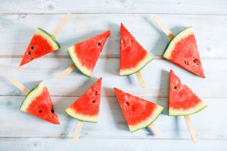 watermelon slice popsicles on light blue wooden background. top view.の写真素材