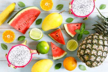 variety of summer fruits, watermelon pineapple mango lime orange dragonfruit, flat lay on light blue wooden background. Summer food concept.の写真素材