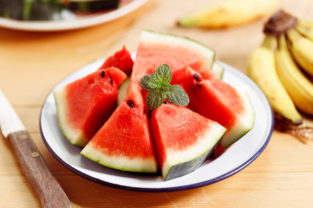 Fresh sliced watermelon in white plate on wooden table. Closeup.の写真素材