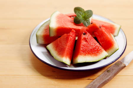 Fresh sliced watermelon in white plate on wooden table. Closeup.の写真素材
