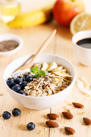 Healthy breakfast with yogurt, granola and fresh blueberries in a bowl on wooden table. Healthy eating and dieting concept.の写真素材