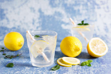 Lemonade iced drink with fresh mint leaves and fresh lemon slices . Cold refreshing drink or beverage with ice on white blue marble background.の写真素材