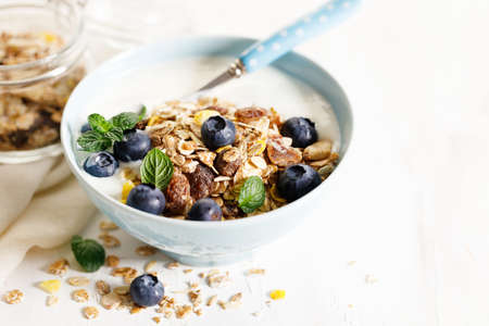 Healthy breakfast with yogurt, granola and fresh blueberries in a bowl on wooden table. Healthy eating and dieting concept.の写真素材