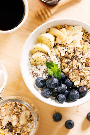 Healthy breakfast with yogurt, granola and fresh blueberries in a bowl on wooden table. Healthy eating and dieting concept.の写真素材