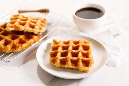 Croffle or Croisant waffle dessert, a marriage between a croissant and a waffle iron. Fresh baked croffle on a white plate. closeup.の写真素材